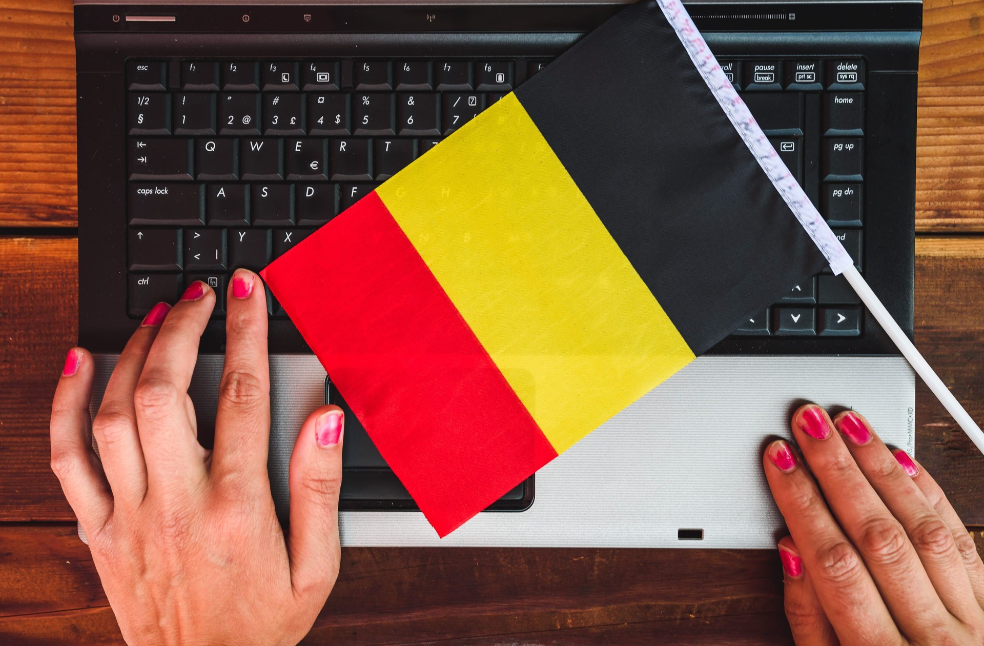 woman hands and flag of Belgium on computer, laptop keyboard